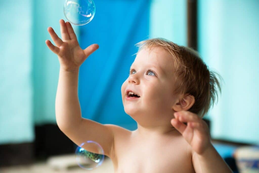 Bebé niña jugando con pompas de jabón